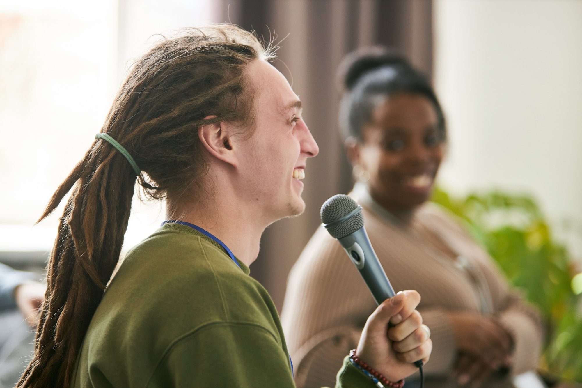 smiling-man-with-dreadlocks-holding-microphone-speaking flipped